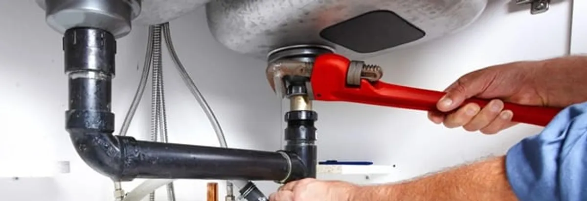 Garbage disposal repair technician tightening the sink drain and disposal connection in Gilbert, AZ