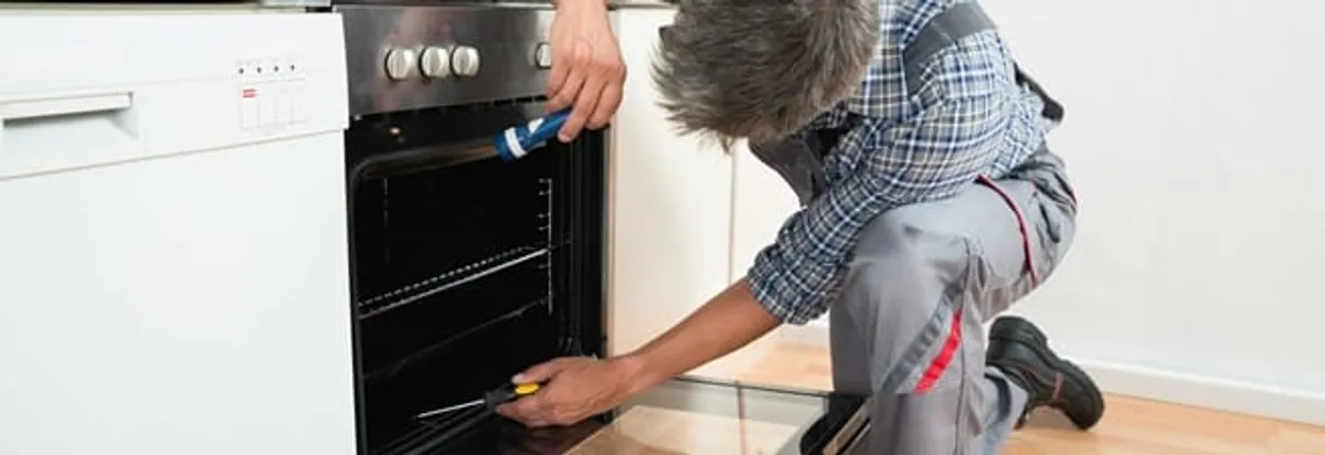 Oven repair technician inspecting and servicing an electric oven in Gilbert, AZ